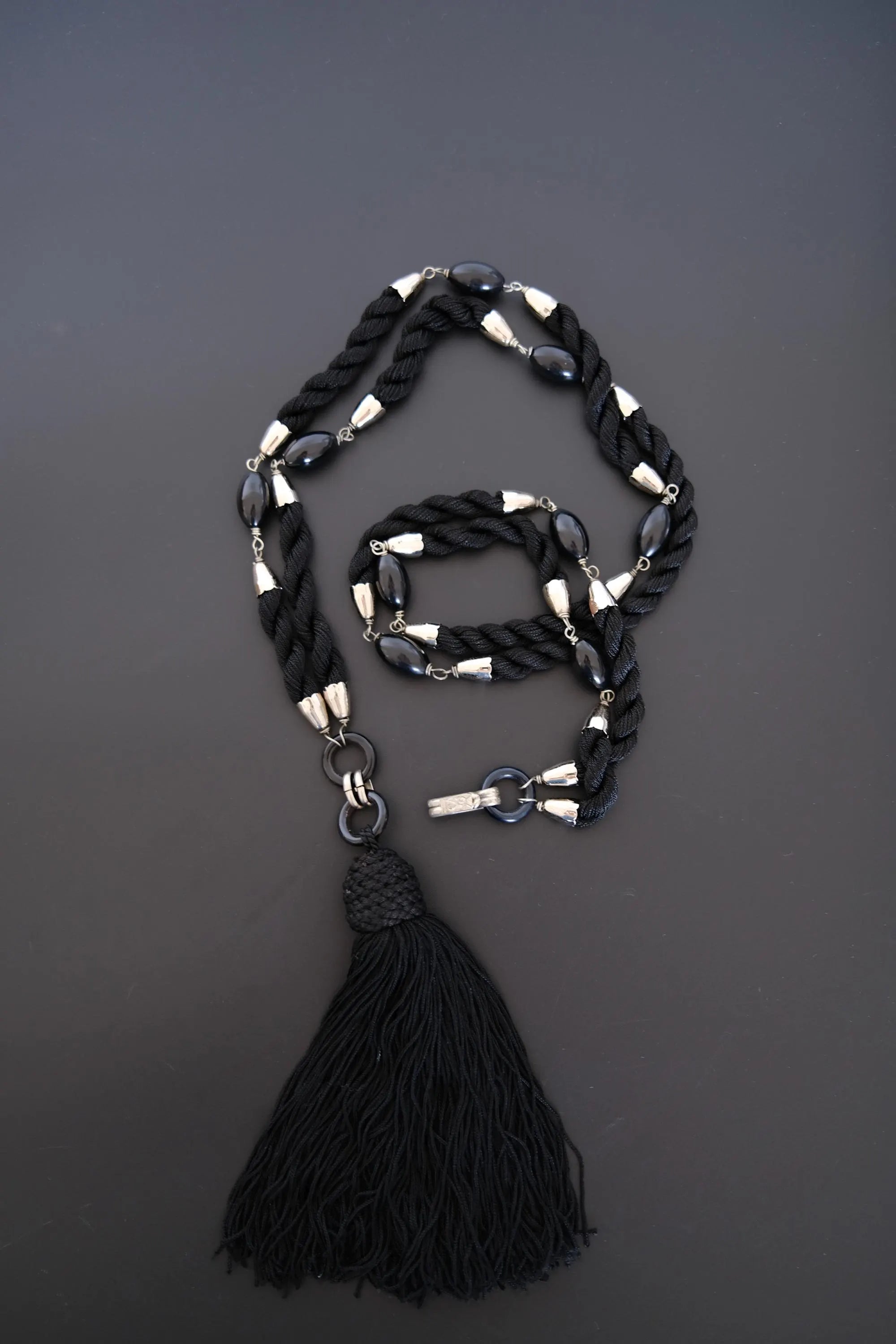 Full view of vintage YSL convertible belt necklace with black braided cords and long fringe tassel