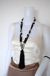 Vintage Yves Saint Laurent long black tassel necklace styled on a mannequin with a satin top
