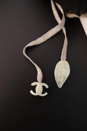 Close-up of neutral-toned textile ribbon cord on vintage CHANEL camellia pendant necklace