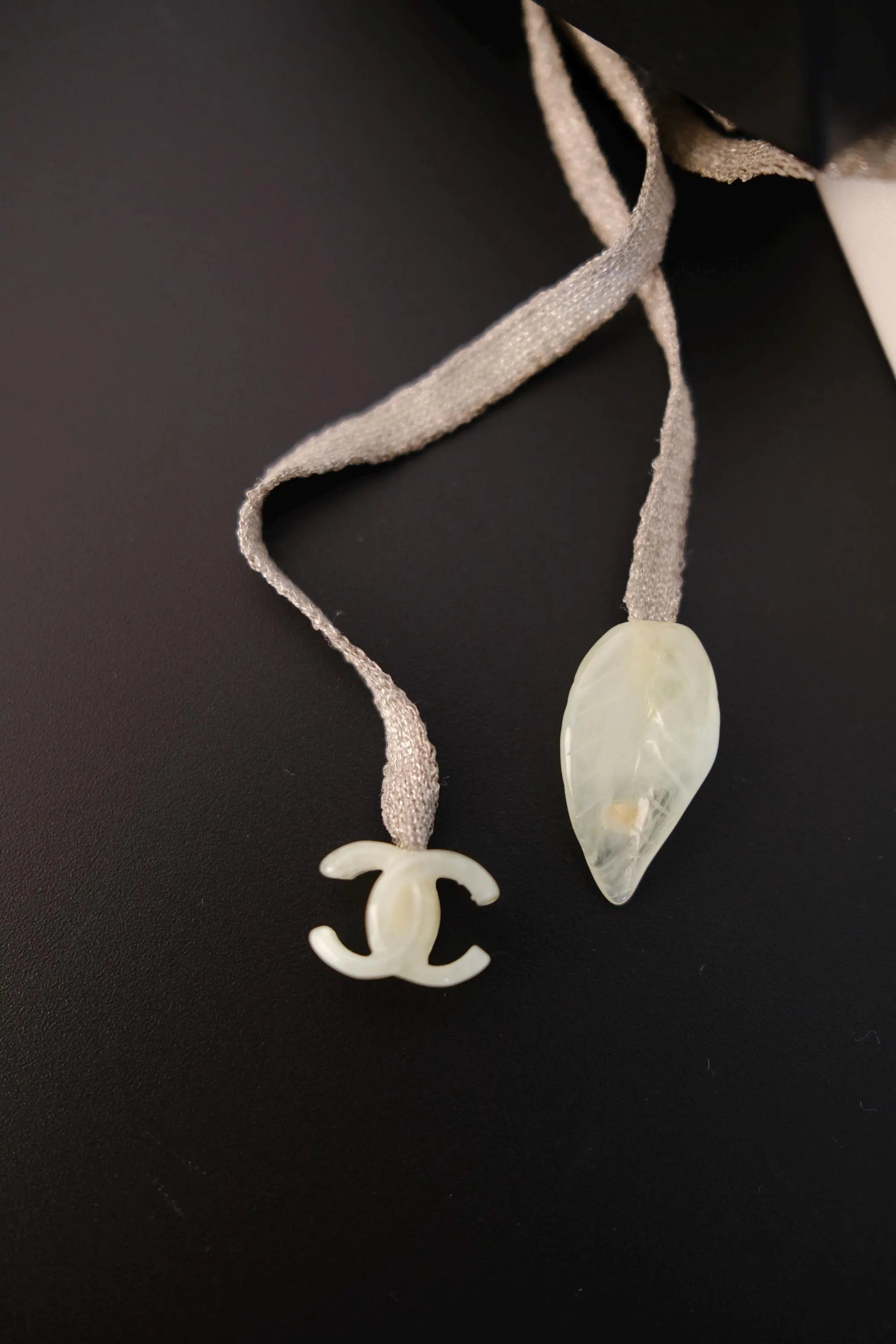Close-up of neutral-toned textile ribbon cord on vintage CHANEL camellia pendant necklace