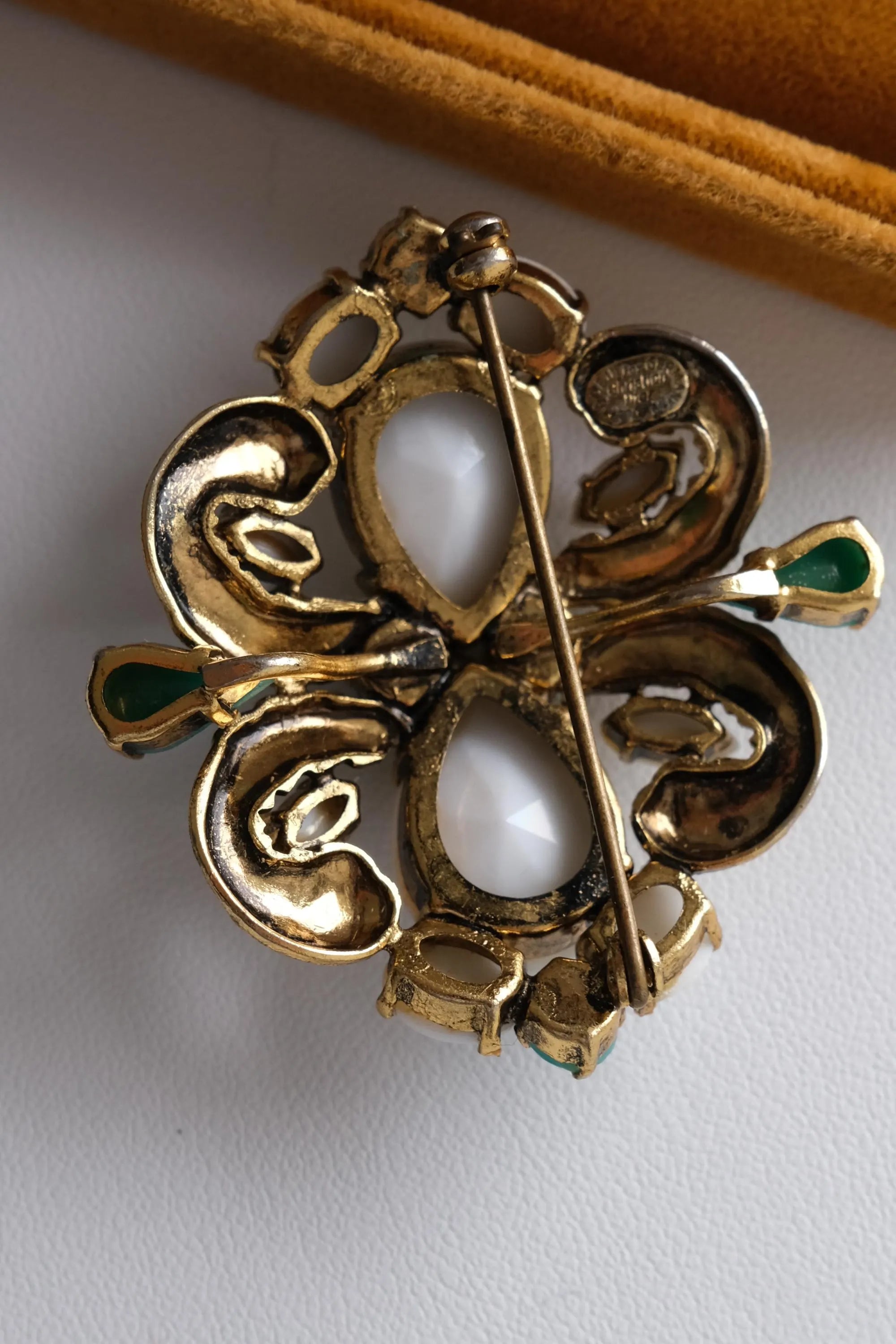 Close up of vintage Christian Dior 1964 brooch featuring milk glass cabochons and gold tone setting