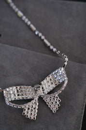 Close-up of sculptural Christian Dior ribbon bow pendant fully embellished with clear crystals and a rectangular center stone