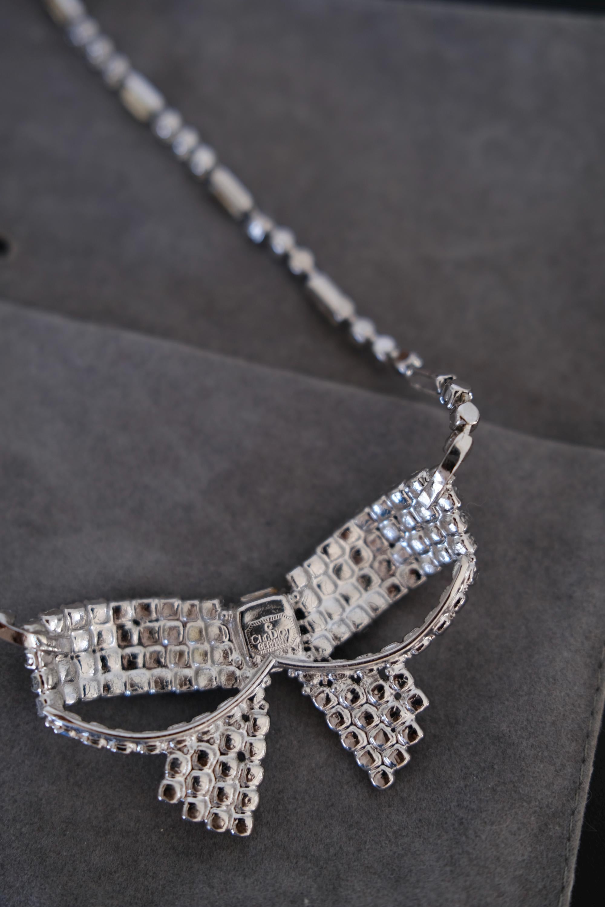 Close-up of sculptural Christian Dior ribbon bow pendant fully embellished with clear crystals and a rectangular center stone