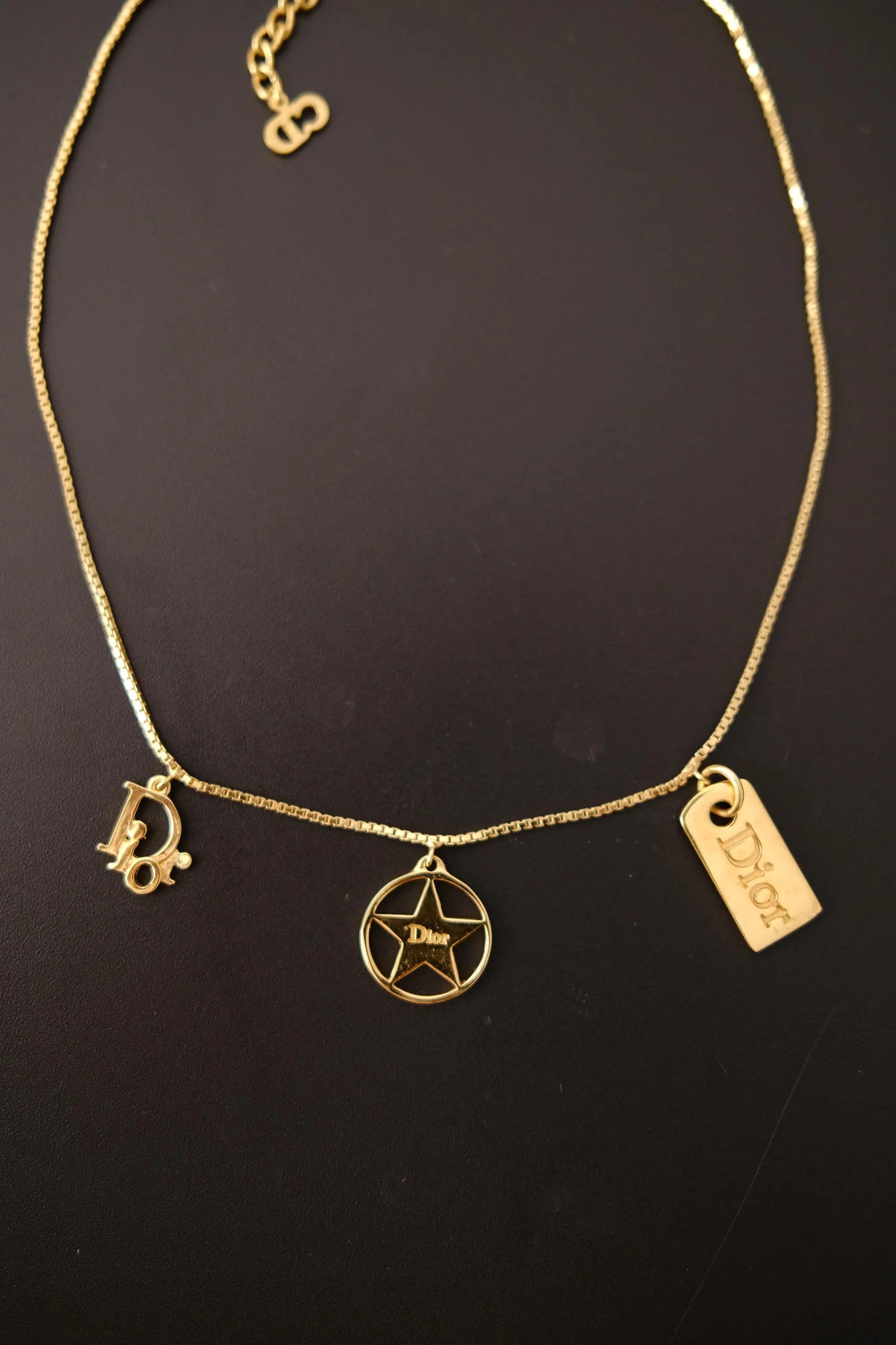 Vintage Christian Dior gold tone necklace featuring three charms with CD logo, openwork star medallion and Dior ID tag