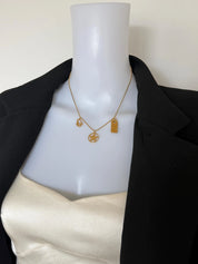 Christian Dior vintage gold charm necklace styled with an elegant black dress showing three signature Dior pendants