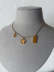 Full view of vintage Christian Dior gold tone chain necklace with three dangling signature Dior charms and adjustable extender