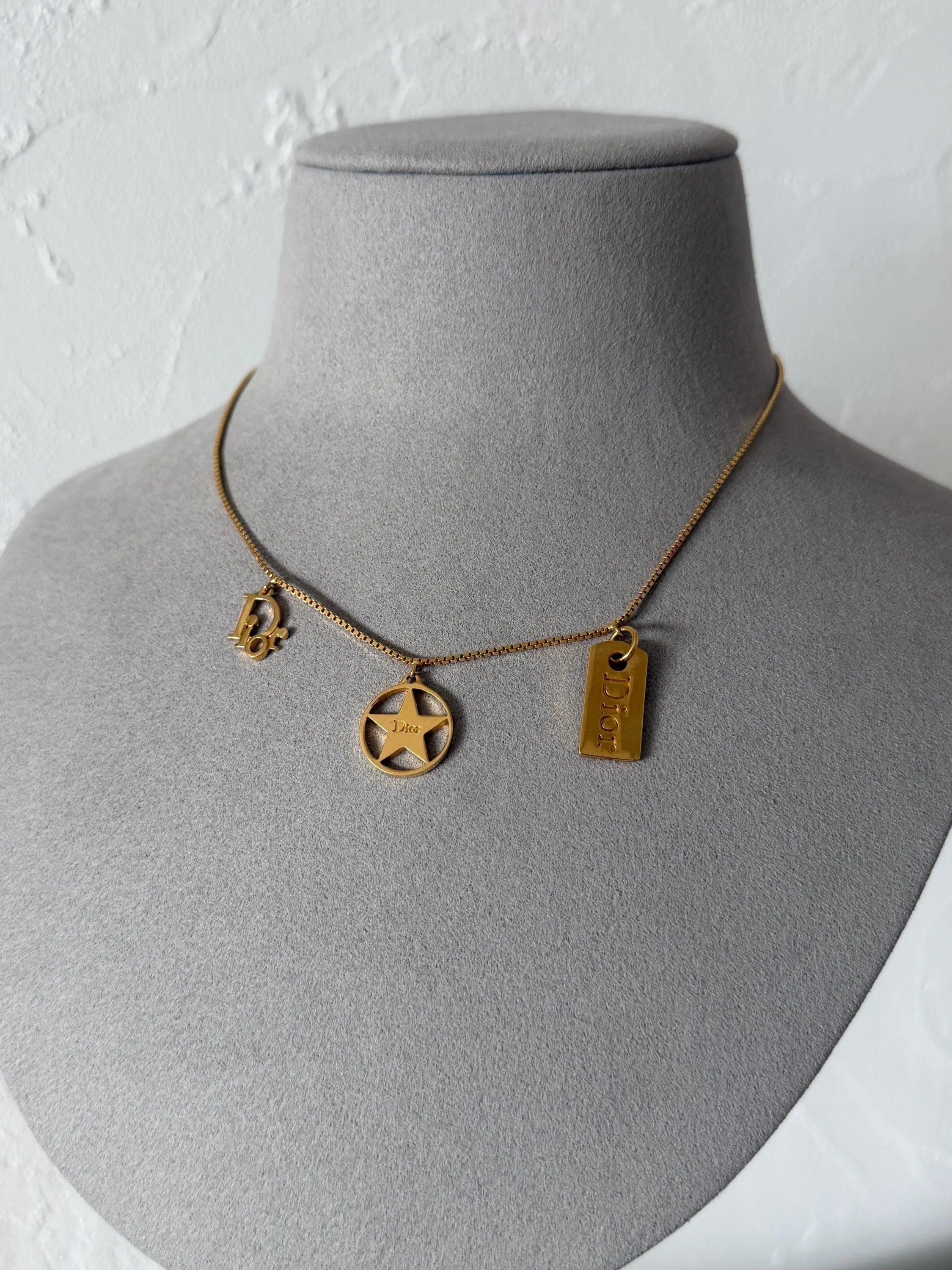 Full view of vintage Christian Dior gold tone chain necklace with three dangling signature Dior charms and adjustable extender
