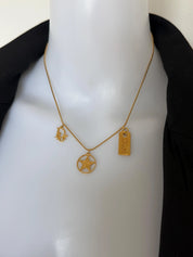 Close-up of three vintage Christian Dior gold charms featuring CD monogram, openwork star and rectangular Dior logo tag