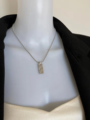Vintage Christian Dior silver-tone rectangular monogram pendant necklace worn at the neckline