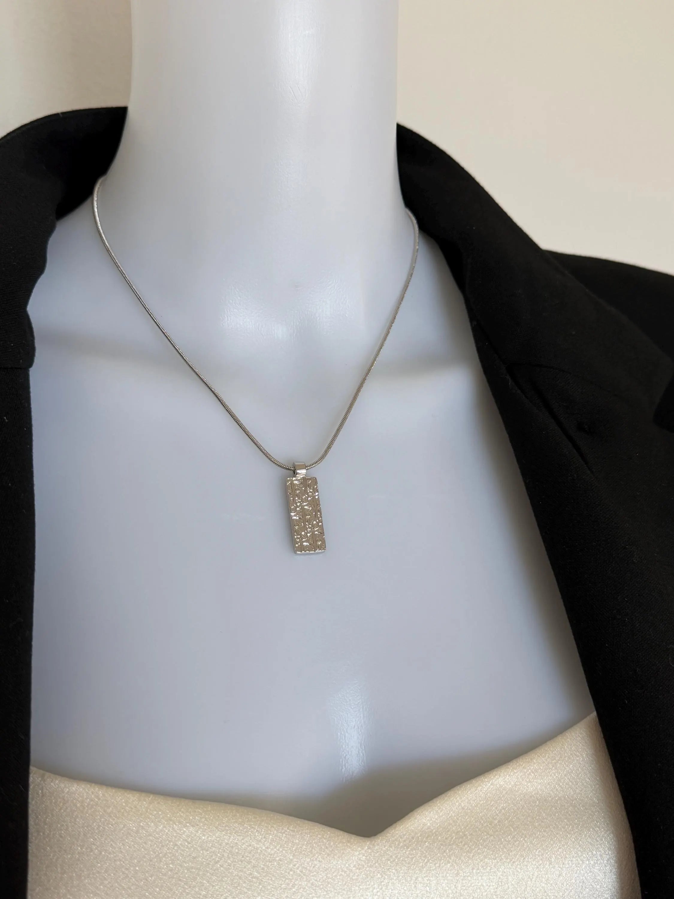 Vintage Christian Dior silver-tone rectangular monogram pendant necklace worn at the neckline