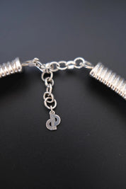 Detailed view of dangling Christian Dior D-logo charm attached to the necklace extension chain