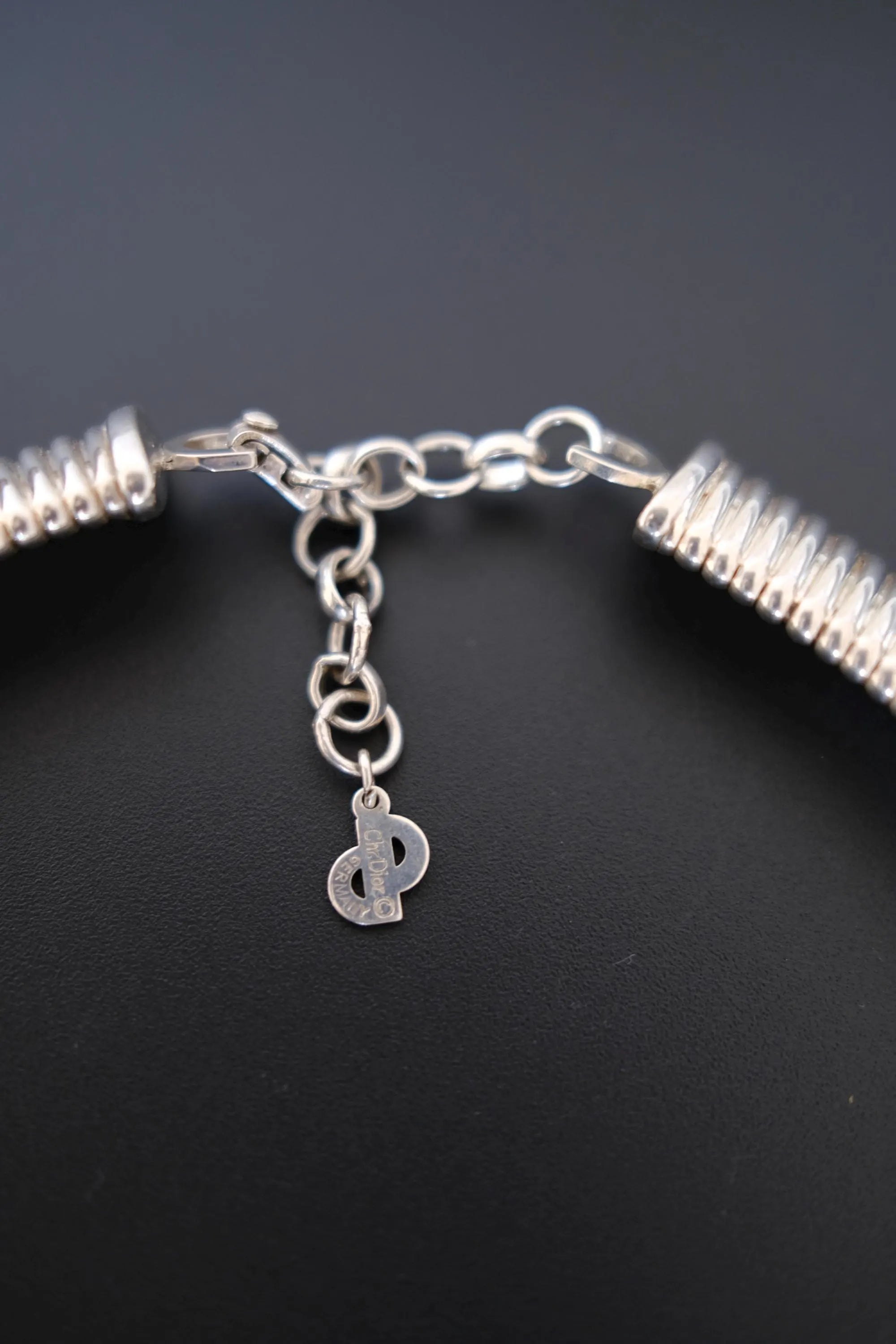 Detailed view of dangling Christian Dior D-logo charm attached to the necklace extension chain