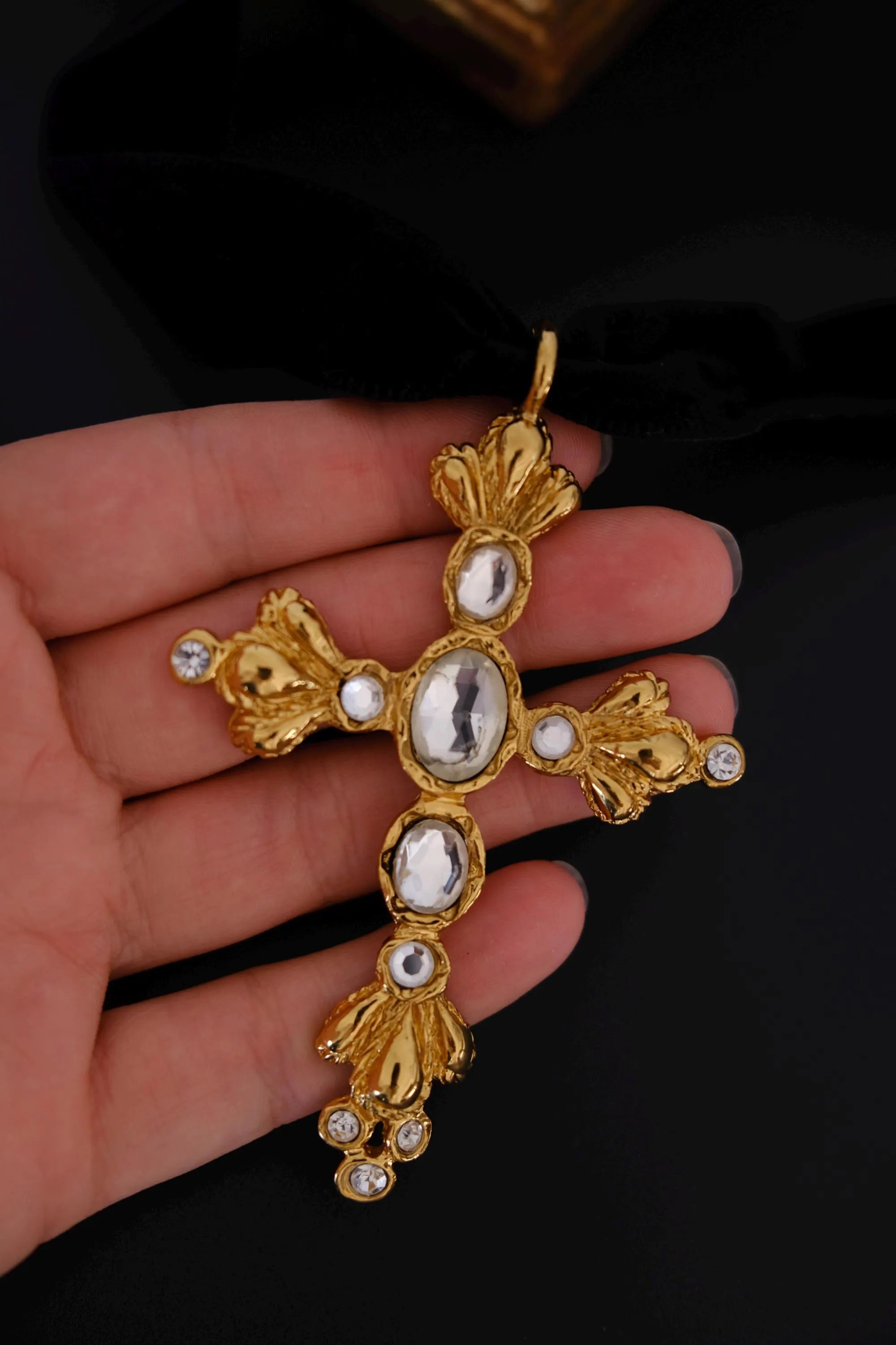 Macro detail of sculptural gold-tone fleur-de-lis inspired ornamentation on Christian Lacroix vintage cross necklace