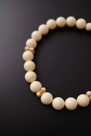 Close-up of round ivory cream beads with subtle linear striped texture on vintage Givenchy necklace