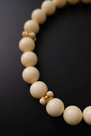Detailed view of sculptural gold-tone spacer elements with matching cream cabochons on Givenchy choker
