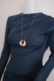 Vintage Givenchy ivory white and gold tone sculptural pendant necklace displayed on a navy blue dress