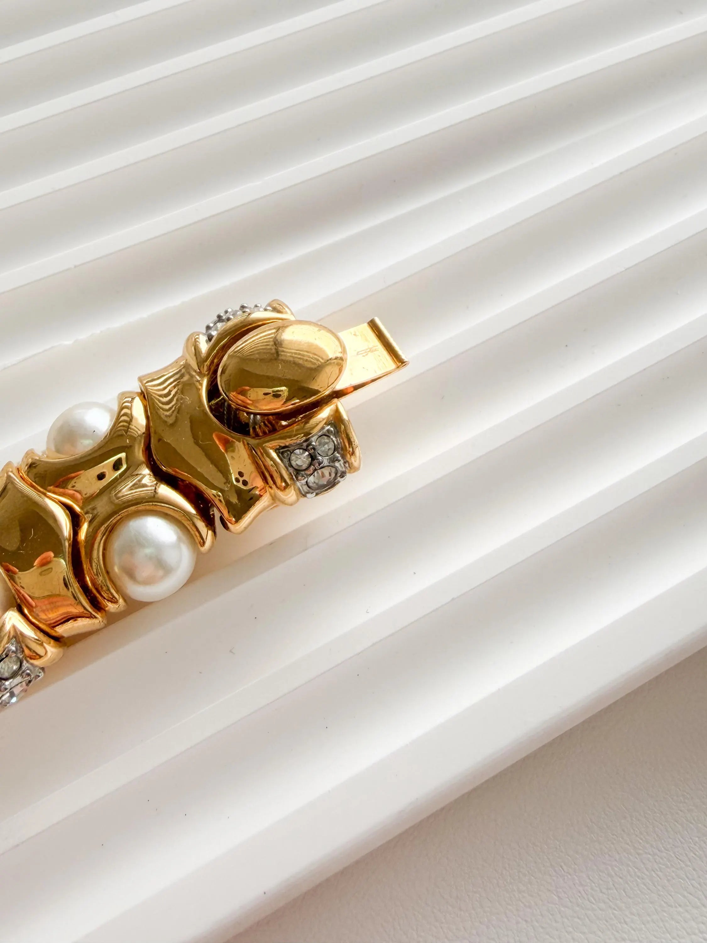 Close up gold choker necklace faux pearl bracelet texture detail