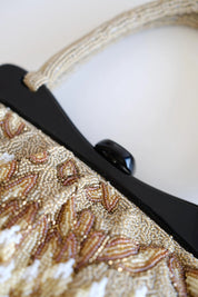 Detailed view of contrasting black structured frame and central clasp on vintage Japanese beaded evening purse