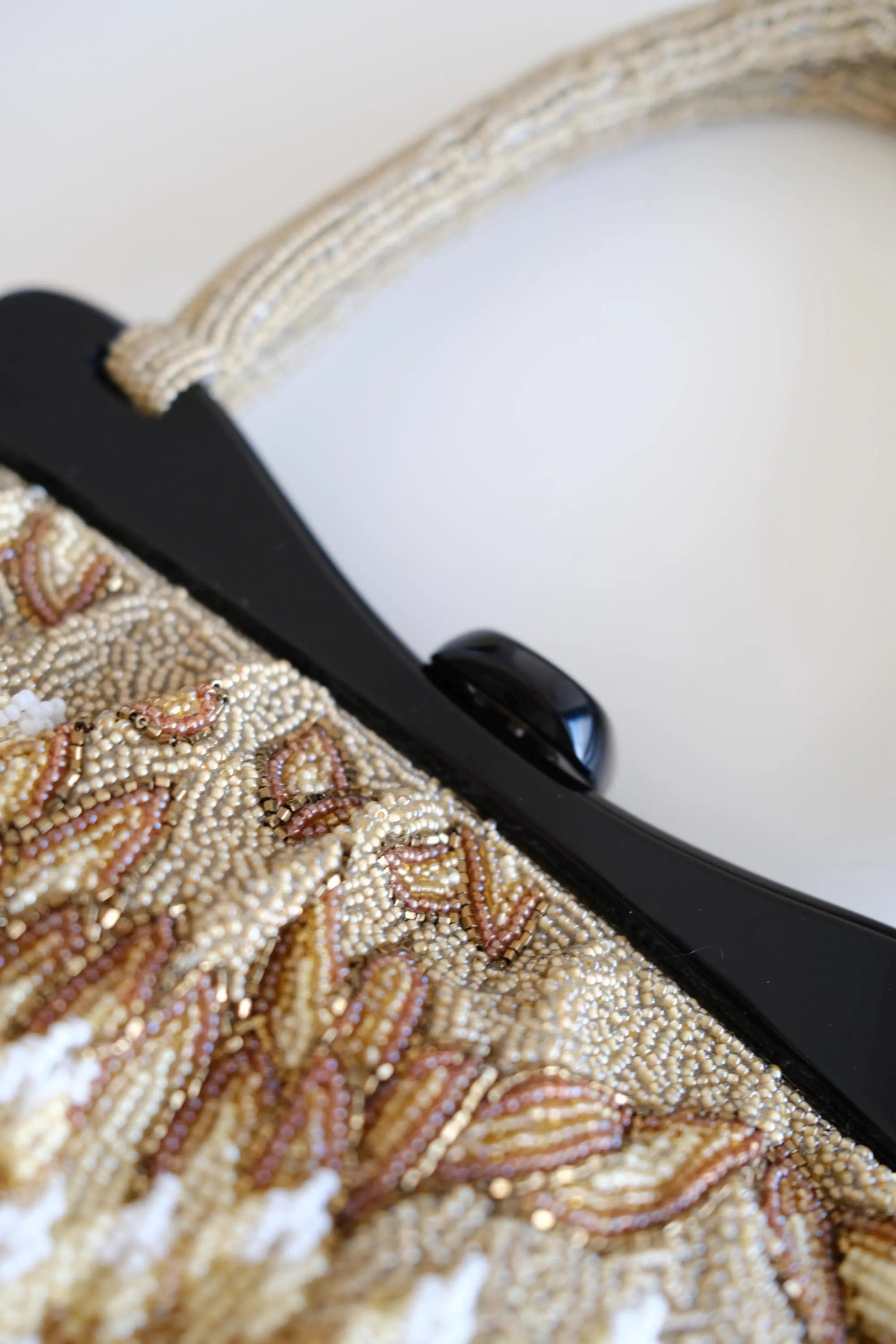 Detailed view of contrasting black structured frame and central clasp on vintage Japanese beaded evening purse