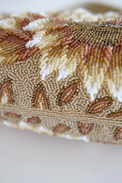 Macro detail of intricate Japanese bead embroidery showing layered floral patterns and textured ivory gold beadwork