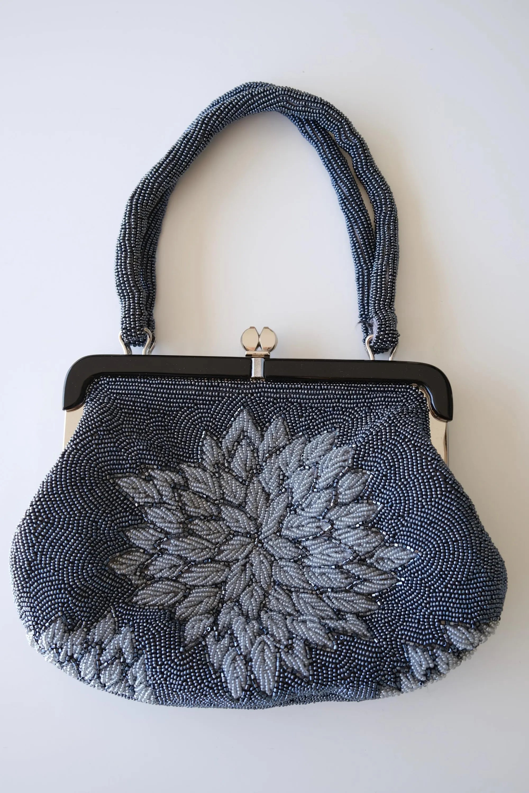Front view of vintage Japanese glass beaded handbag with large dimensional silver-grey peony flower against blue-grey beaded background