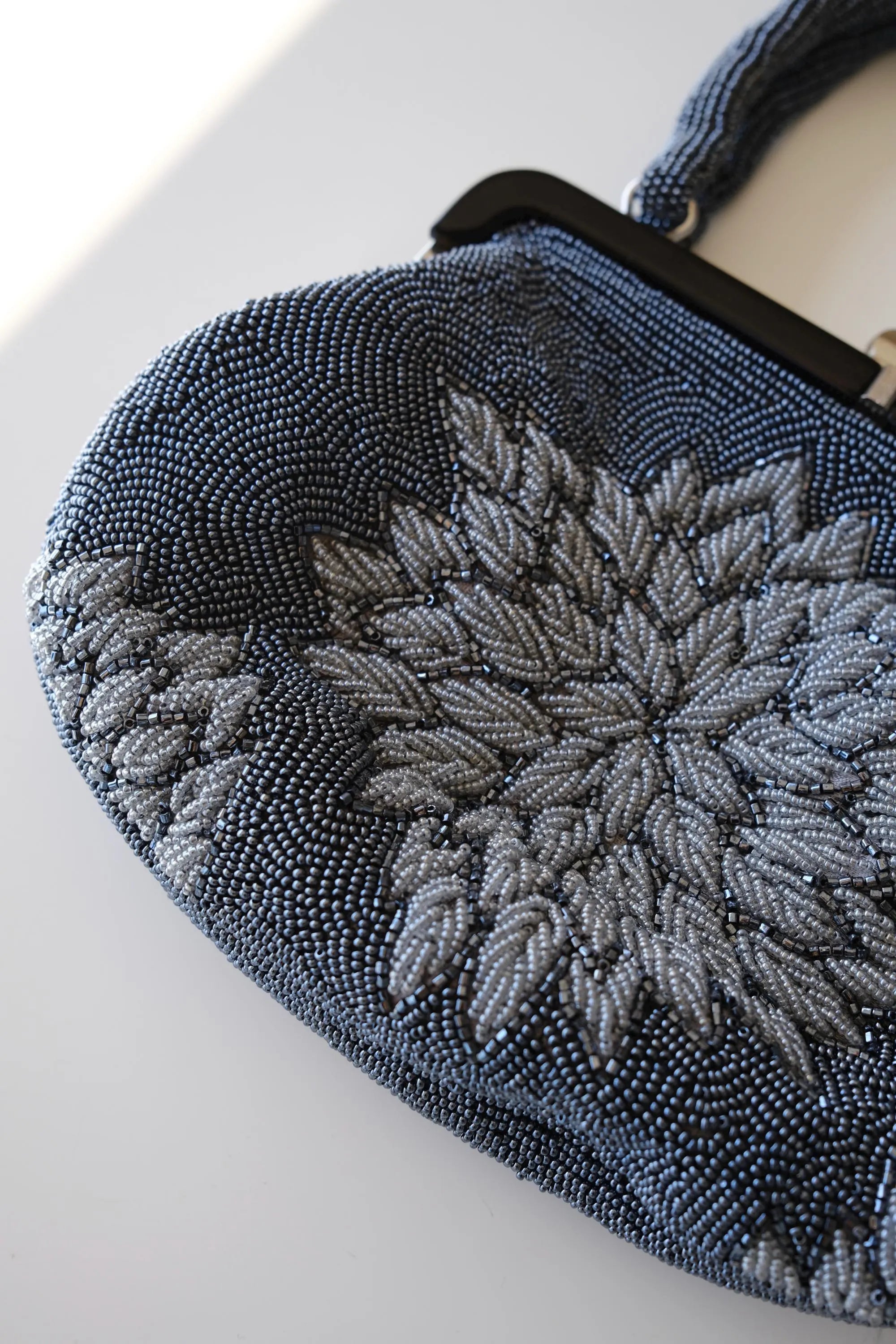 Close-up of raised three-dimensional peony flower embroidery made with silver-grey glass seed and bugle beads