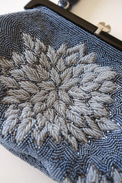 Macro detail of intricate Japanese glass seed and bugle bead embroidery in blue-grey, silver-grey and charcoal