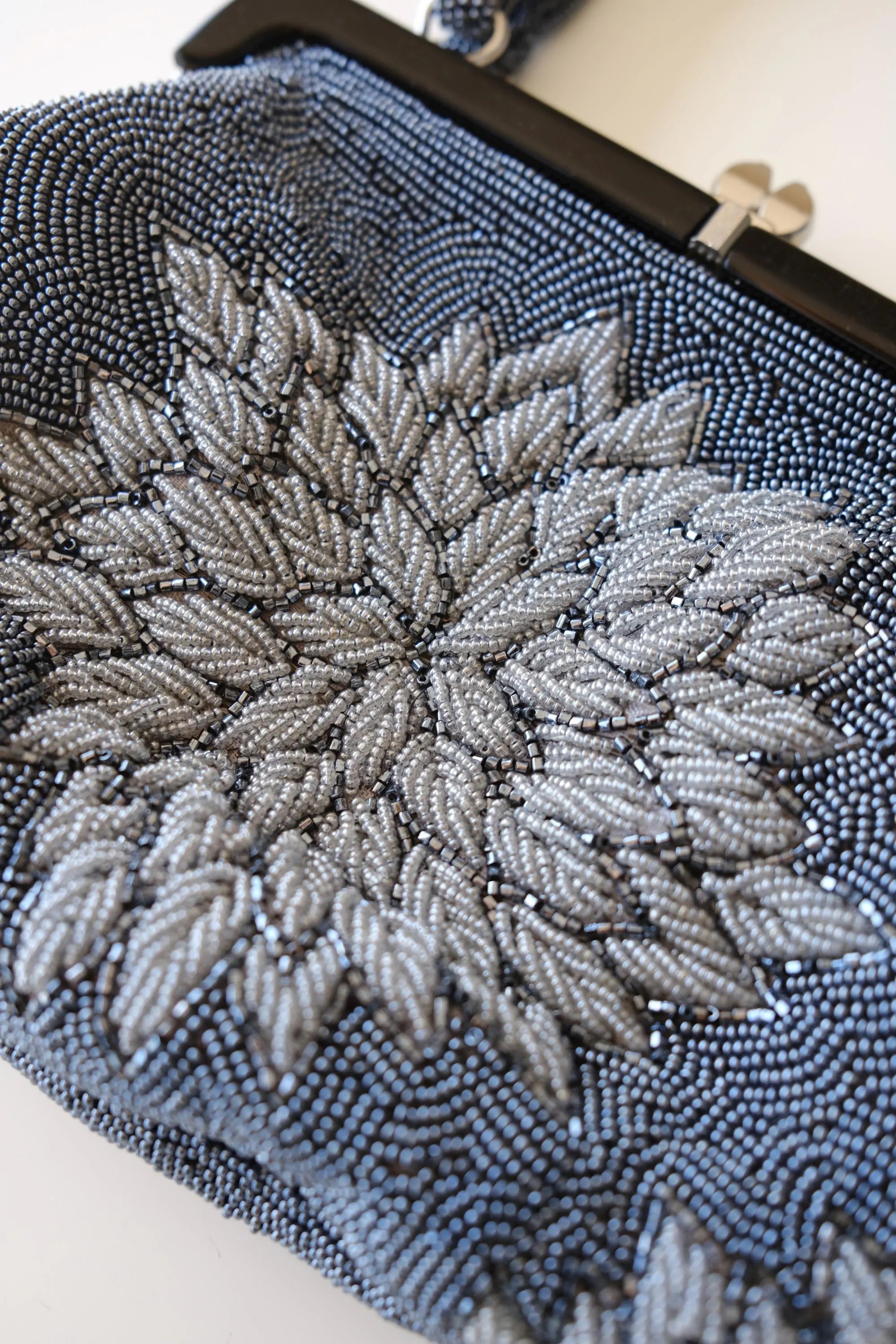 Macro detail of intricate Japanese glass seed and bugle bead embroidery in blue-grey, silver-grey and charcoal
