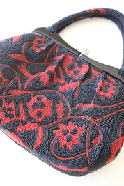 Detailed view of stylized deep red floral motifs on densely beaded black Japanese vintage evening bag