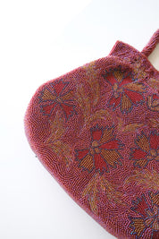 Close-up of intricate Japanese glass seed bead and bugle bead embroidery in burgundy, blue, gold and green