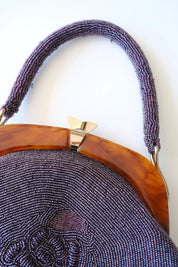 Close-up of decorative gold-tone clasp closure on amber-tone frame of vintage Japanese purple beaded handbag