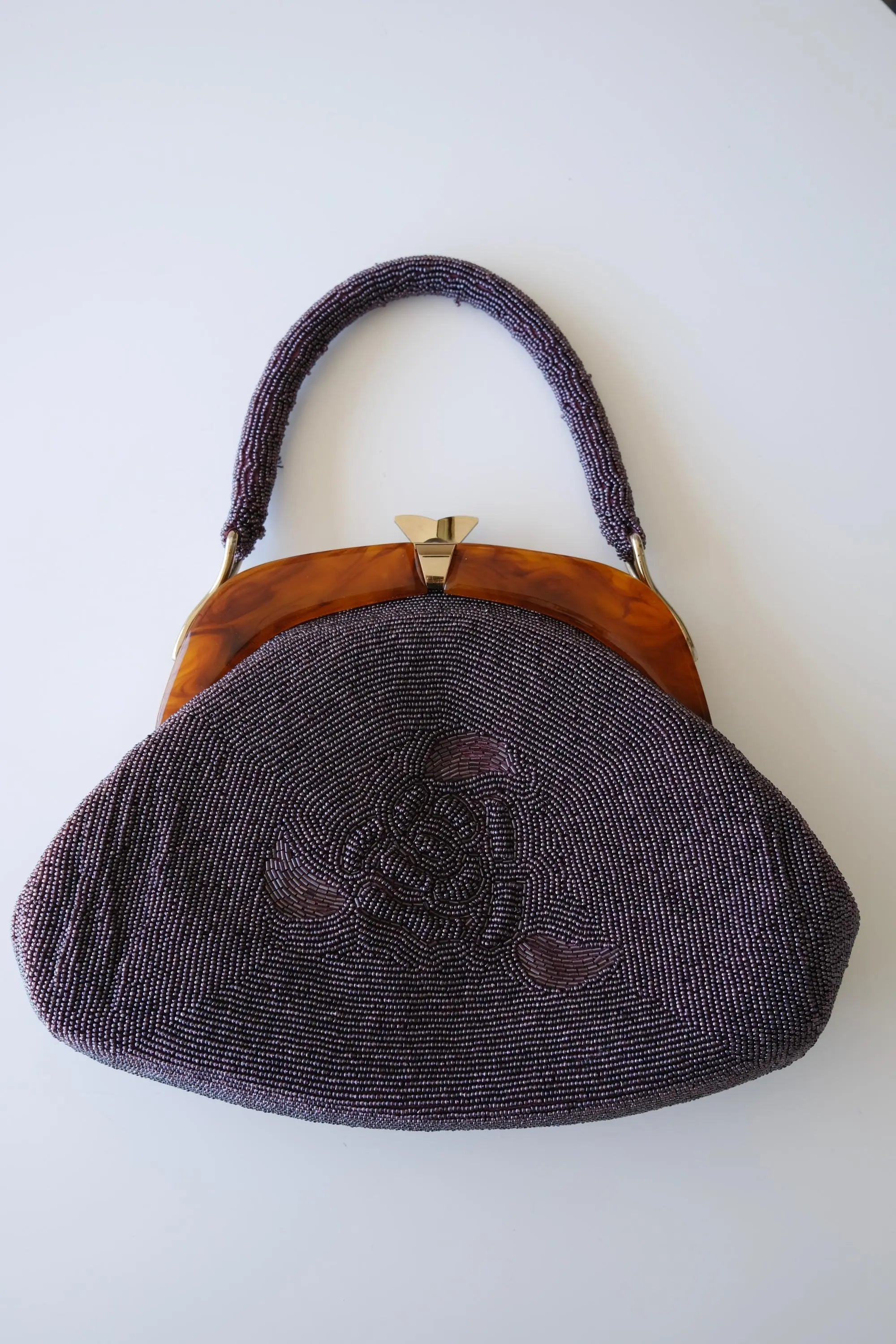 Front view of vintage Japanese purple glass seed beaded handbag featuring dimensional rose and floral motifs