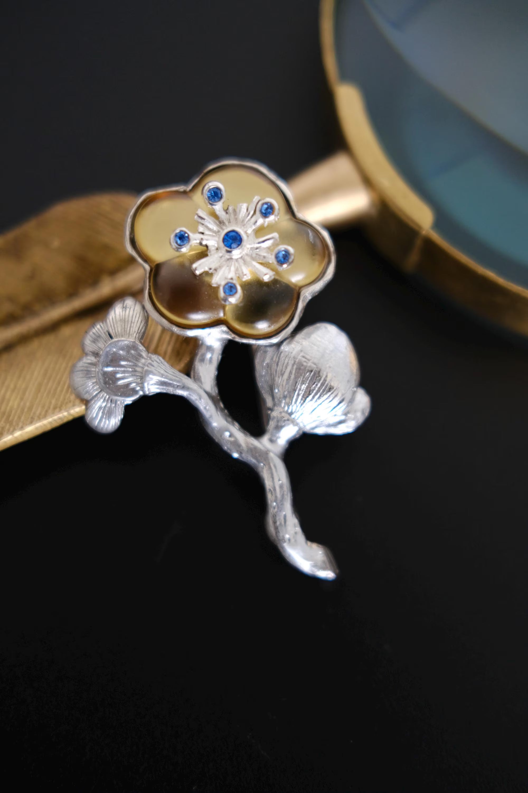 Vintage KENZO flower brooch with blue crystals, champagne gold floral detail and sculptural silver tone leaves, made in France