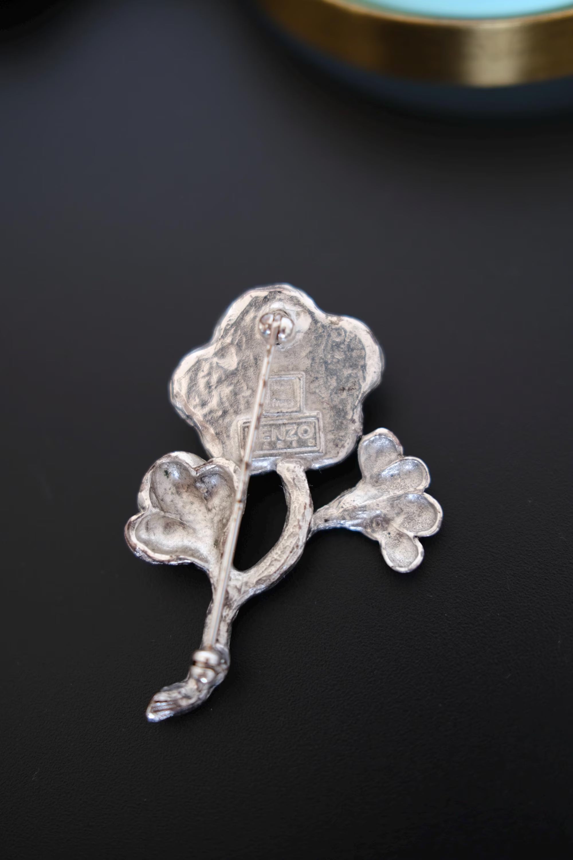 Reverse of vintage KENZO flower brooch showing signed KENZO designer mark