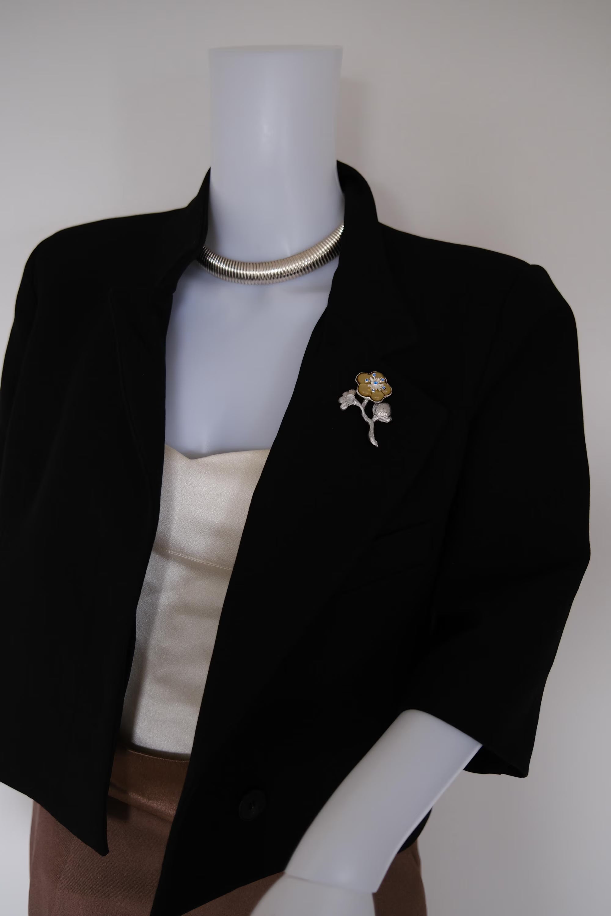 Vintage KENZO blue crystal flower brooch styled on a tailored blazer with elegant silver and gold tone floral design