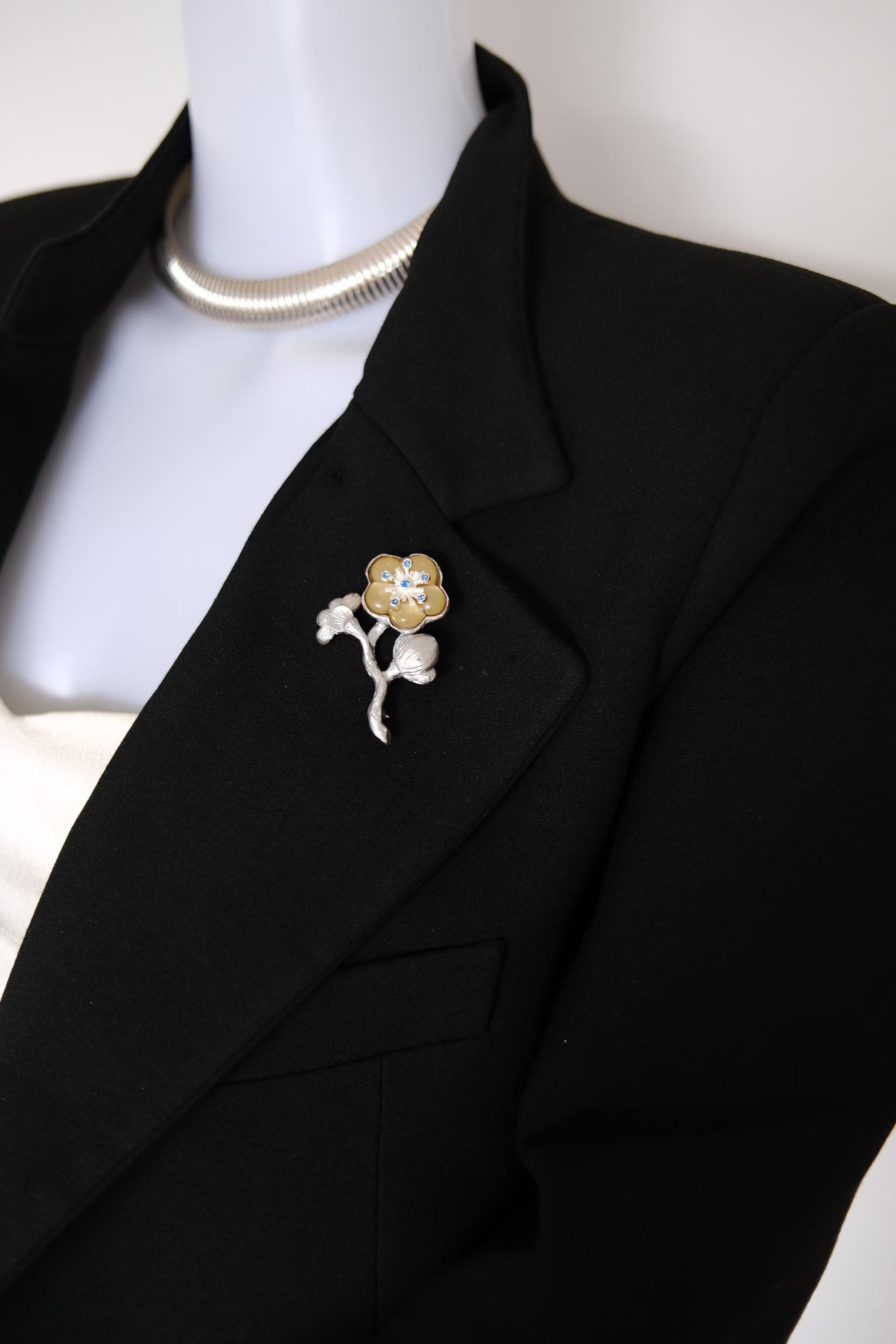 KENZO vintage silver and champagne gold floral brooch with blue crystal accents worn on a coat