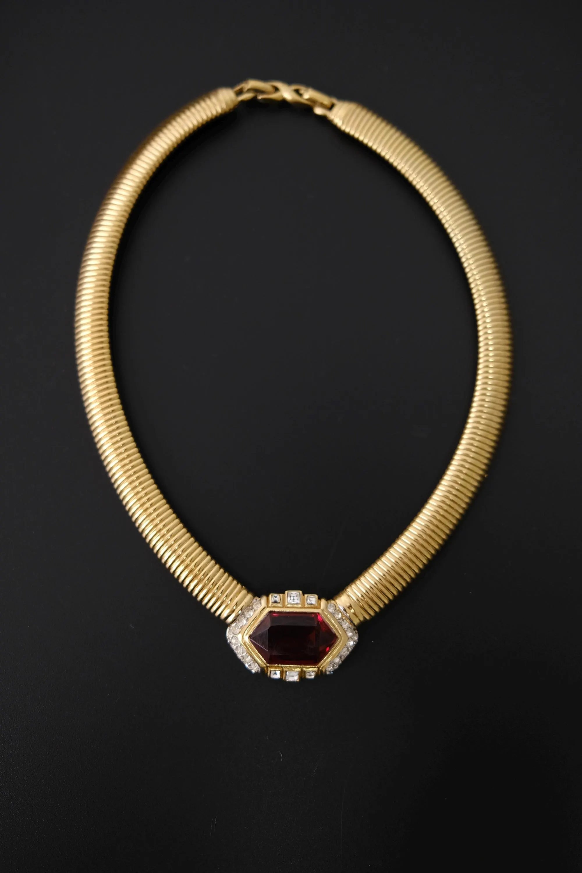 Vintage Nina Ricci gold-tone Tubogas collar necklace with large faceted ruby-red glass centerpiece and clear crystal accents