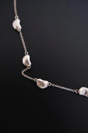 Close-up of TIFFANY & CO signature marking on vintage Elsa Peretti Five Bean silver necklace