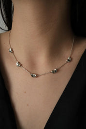 Vintage Tiffany & Co Elsa Peretti Five Bean sterling silver necklace worn around the neckline showing five delicate silver Bean motifs
