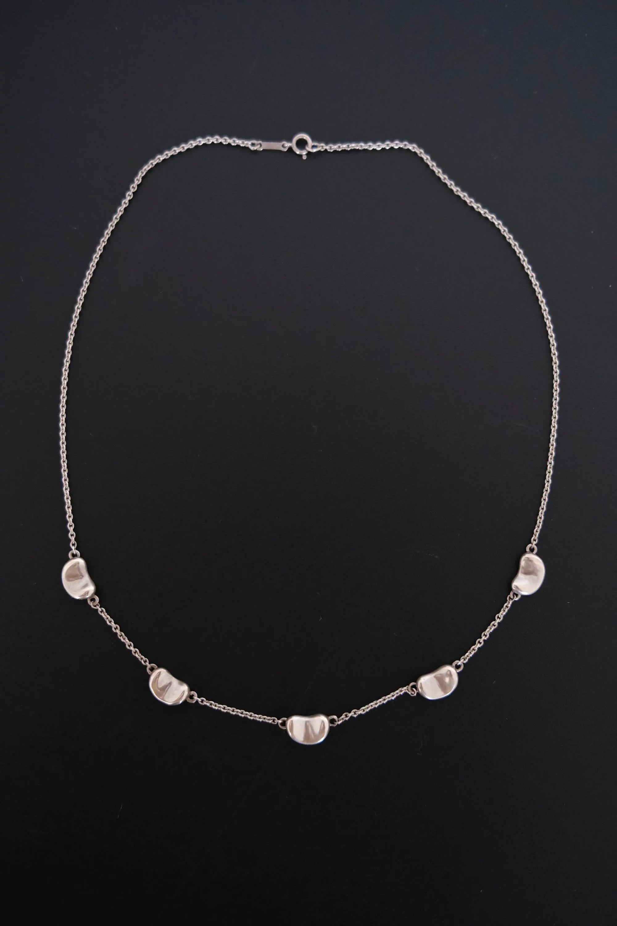 Full view of vintage Tiffany & Co Elsa Peretti Five Bean necklace with five sculptural silver motifs along a fine chain