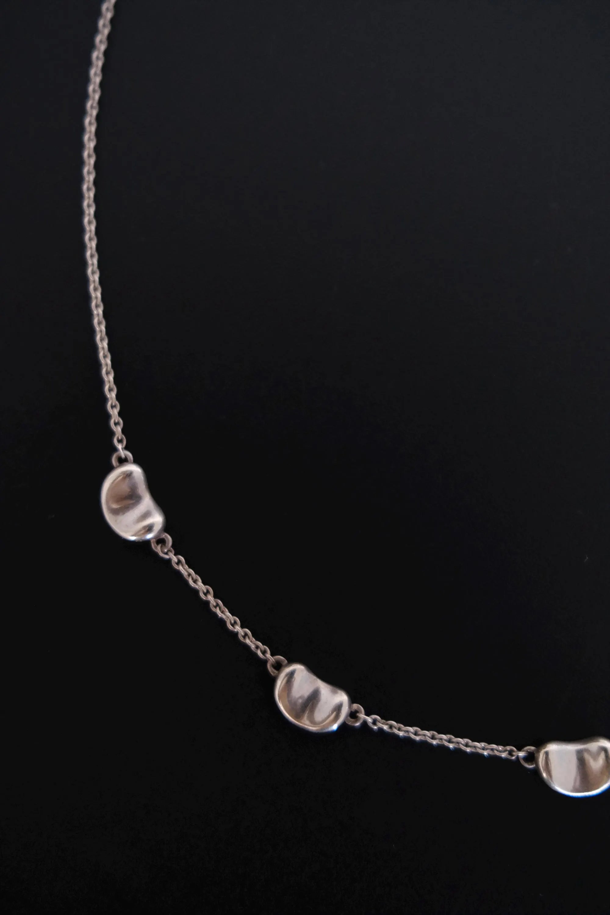 Detailed view of smooth sculptural Bean design on Tiffany & Co Elsa Peretti vintage sterling silver necklace