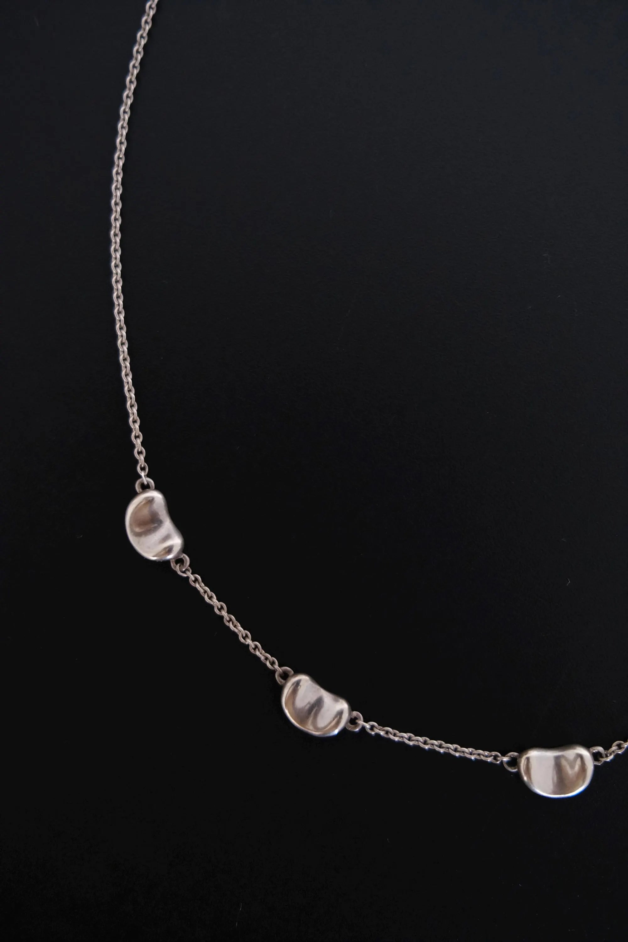 Detailed view of smooth sculptural Bean design on Tiffany & Co Elsa Peretti vintage sterling silver necklace