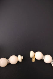 Screw-style closure on vintage Yves Saint Laurent beige beaded necklace with YSL logo charm