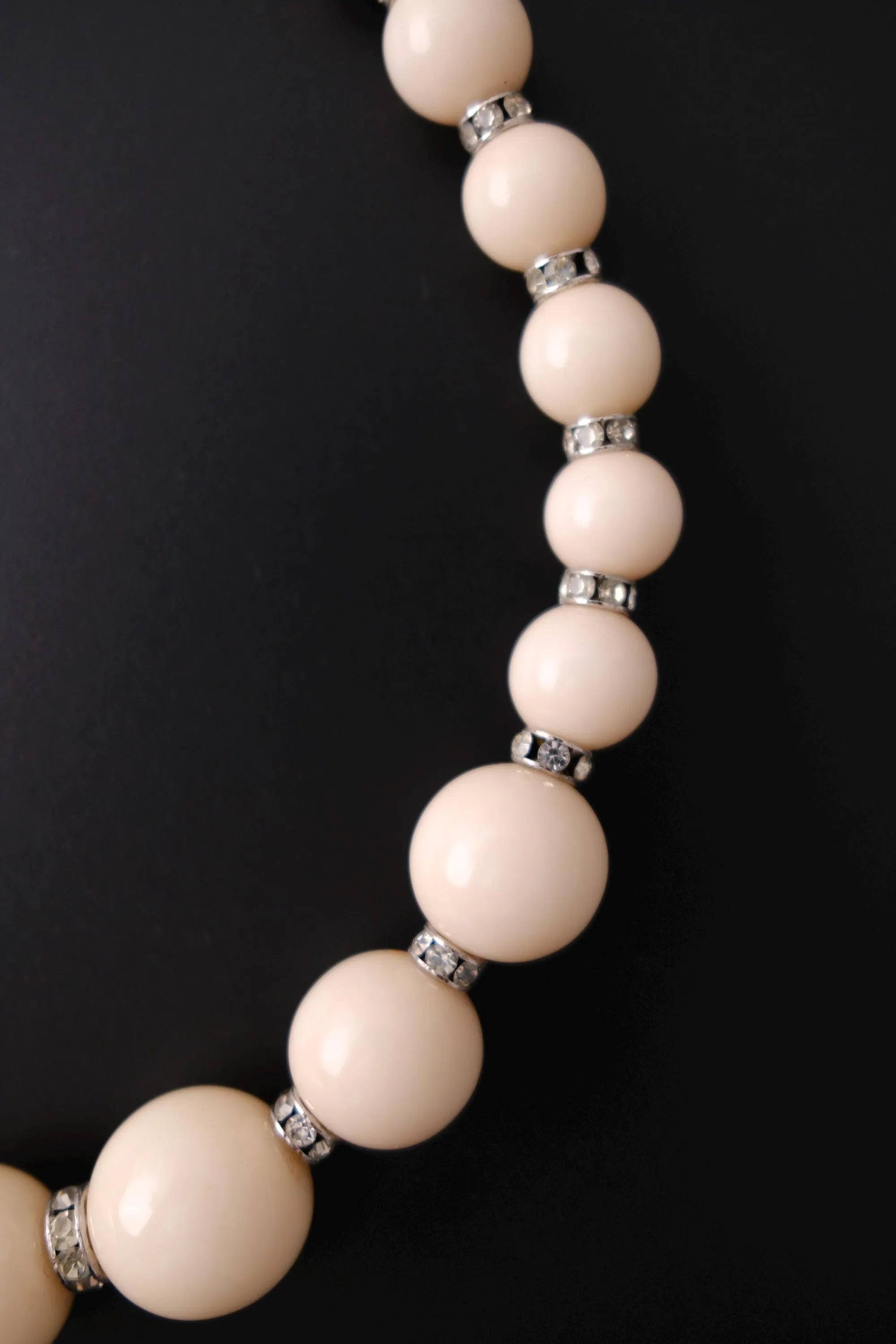 Detailed view of sparkling clear crystal rhinestone rondelle spacers between beige beads on YSL necklace