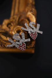 Front view of vintage YSL silver tone earrings with clear crystal logo and red hearts