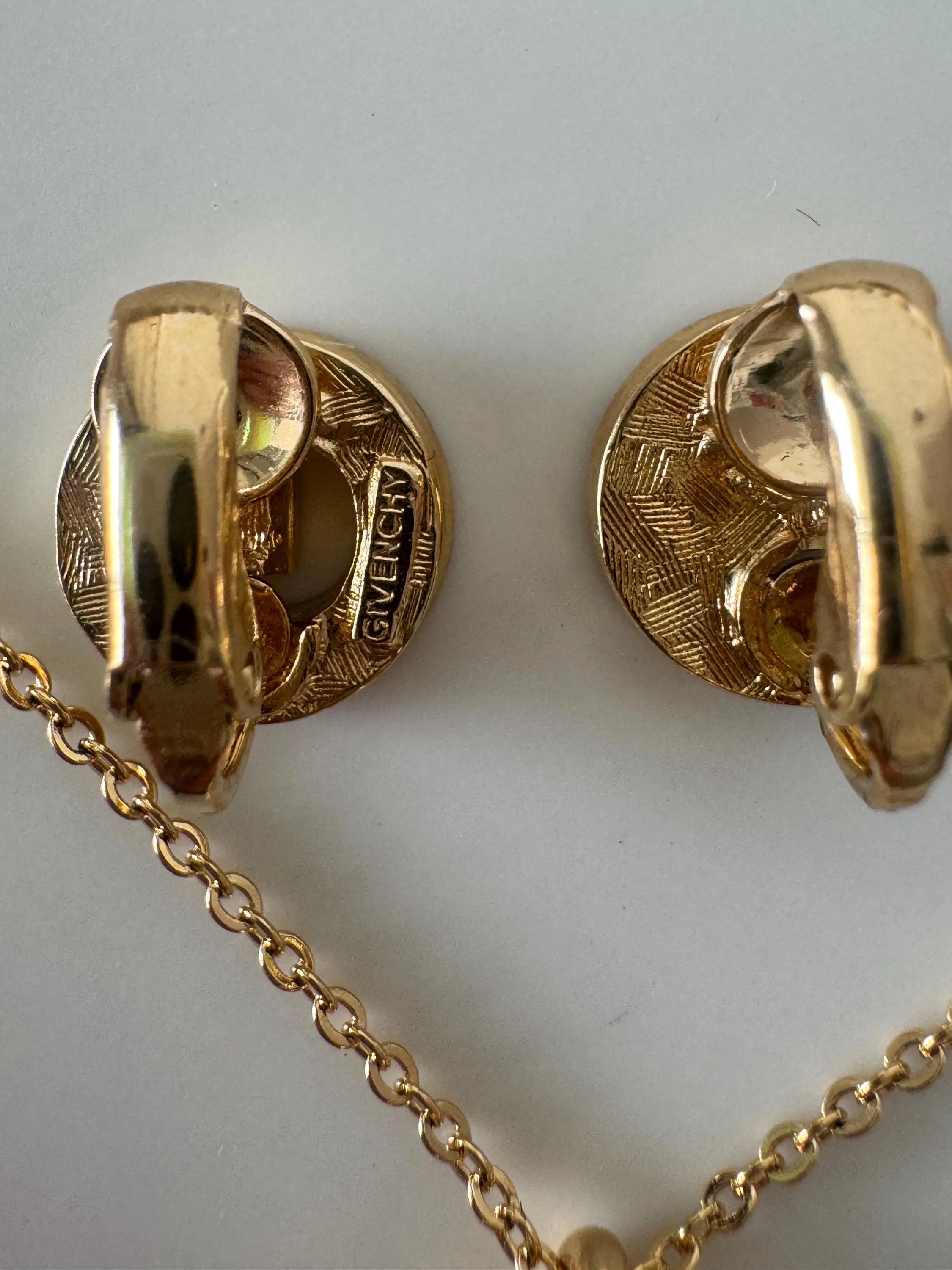Close-up of Vintage Givenchy G logo crystal rhinestone earrings in gold tone