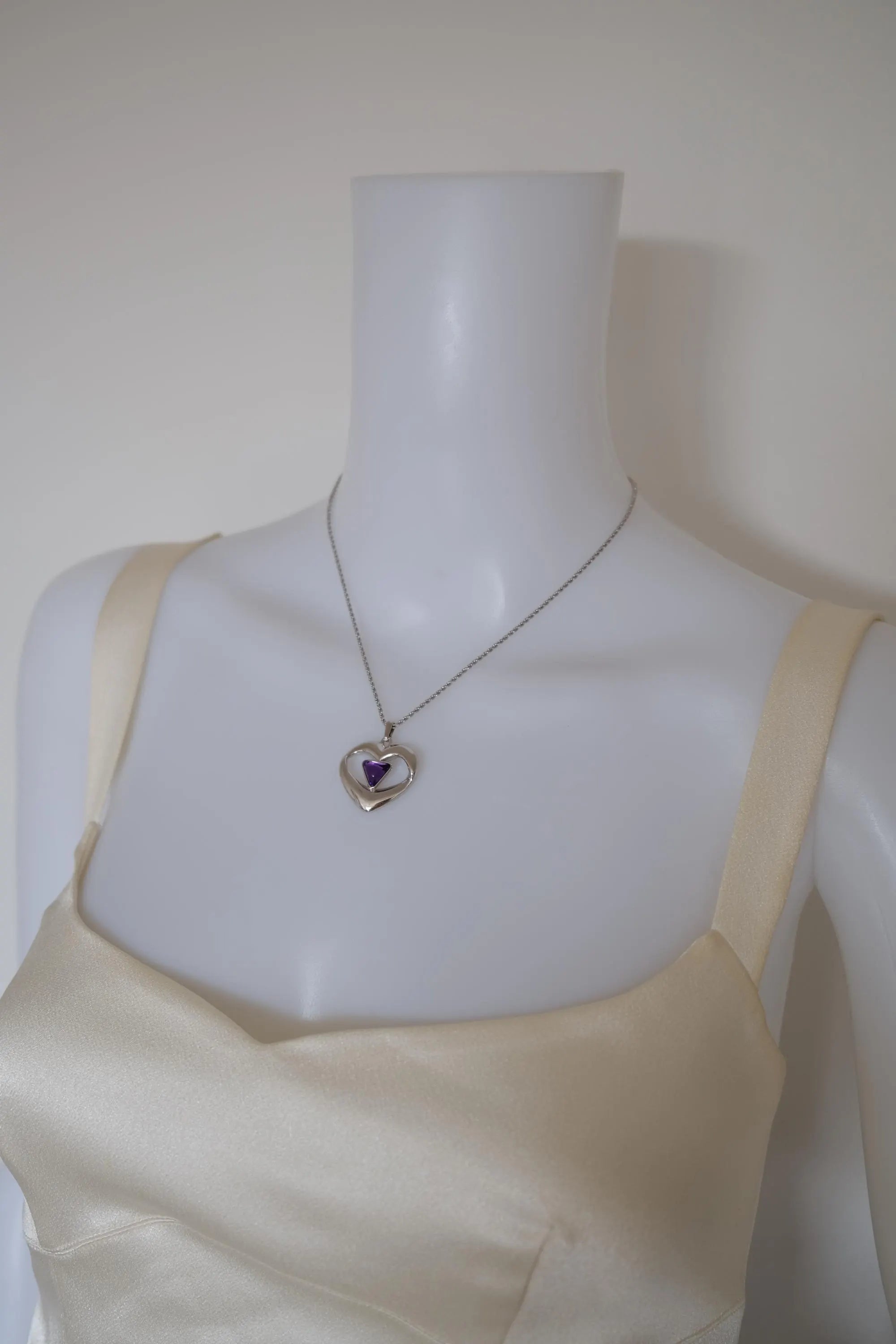 Vintage YSL Yves Saint Laurent silver-tone heart necklace with purple cabochon worn around the neck