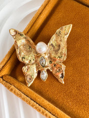 Vintage Yves Saint Laurent gold butterfly brooch with pearl and rhinestone accents, timeless couture elegance