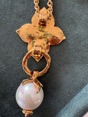 Close-up of YSL gold clover pendant with large faux pearl charm
