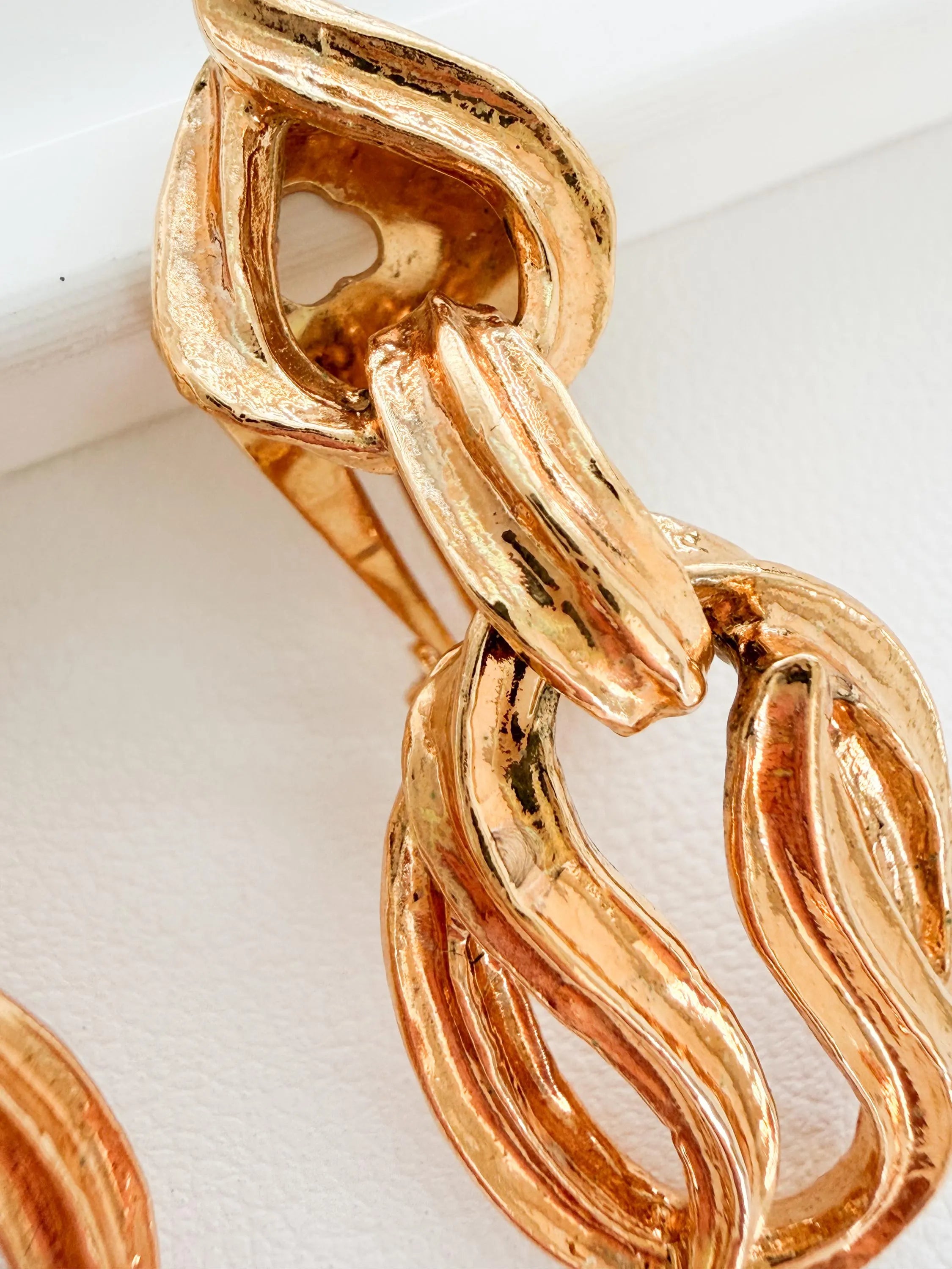 Close-up of textured gold tone sculptural links on vintage YSL earrings